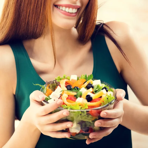 Schöne junge Frau isst Salat, drinnen — Stockfoto