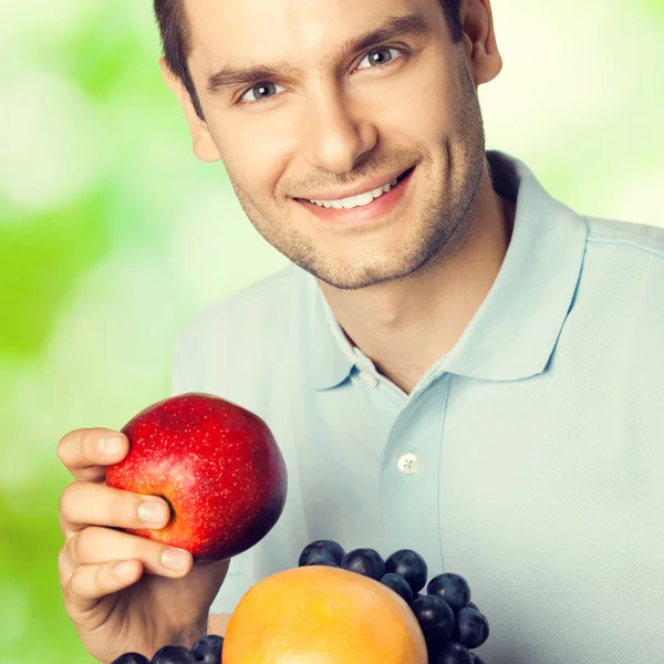 Šťastný usmívající se muž s talíř ovoce, venku — Stock fotografie