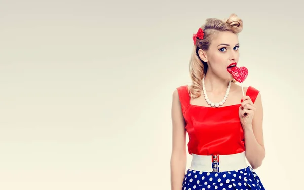 Mladá žena jíst barevné lízátko, oblečený v pin-up styl — Stock fotografie