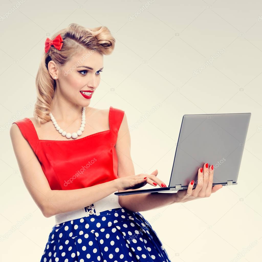 woman holding laptop, dressed in pin-up style dress