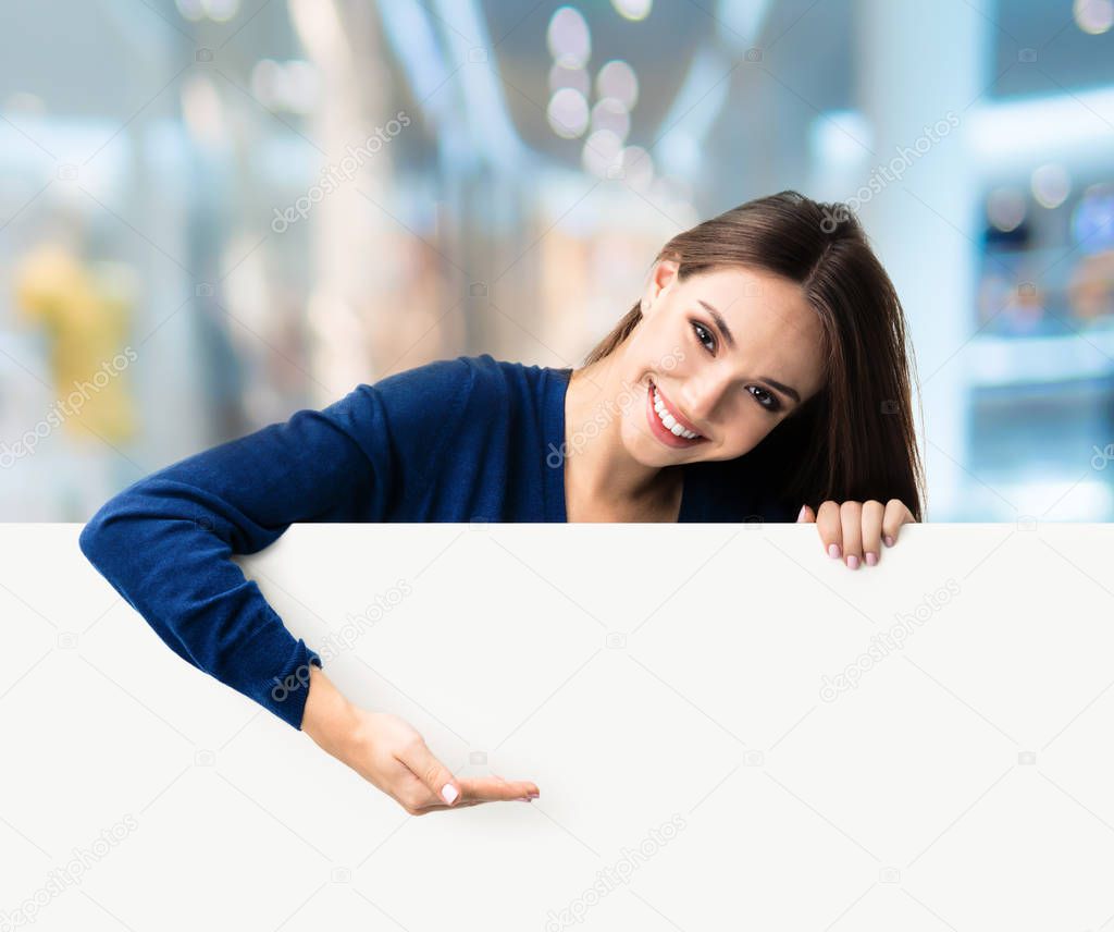 Brunette woman in casual clothing showing blank signboard, at ma