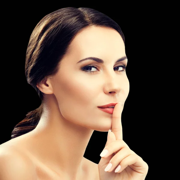 Woman keeping finger on her lips, isolared on black — Stock Photo, Image