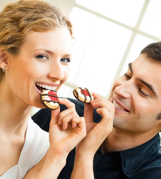 Portrait of young happy couple eating cakes — Stock Photo, Image