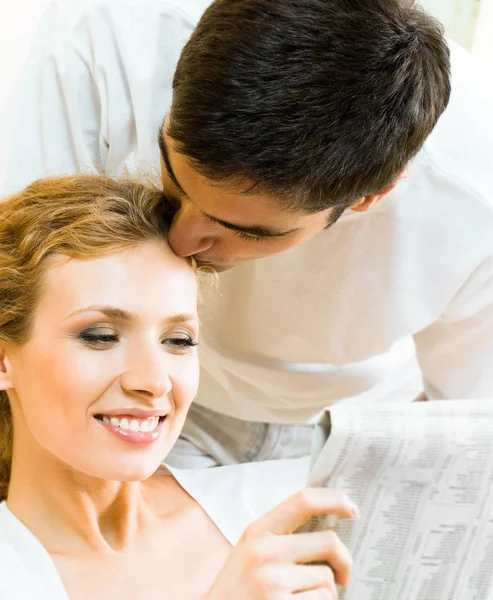 Joven feliz pareja amorosa leyendo el periódico en casa —  Fotos de Stock