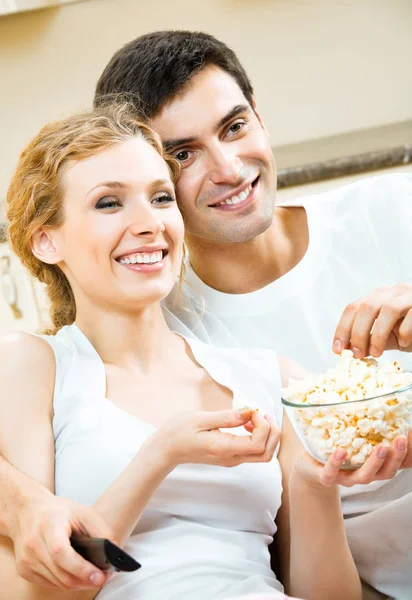 Mladý pár jíst popcorn a sledování televize — Stock fotografie