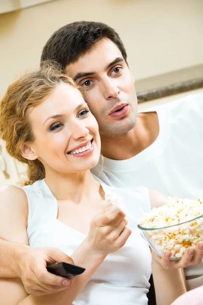 Молодая пара ест попкорн и смотрит телевизор — стоковое фото