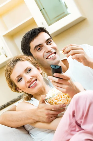 Pareja joven comiendo palomitas de maíz y viendo televisión —  Fotos de Stock