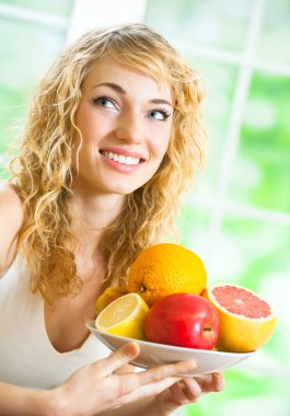 Genç mutlu gülümseyen kadın kapalı meyvelerin plakalı