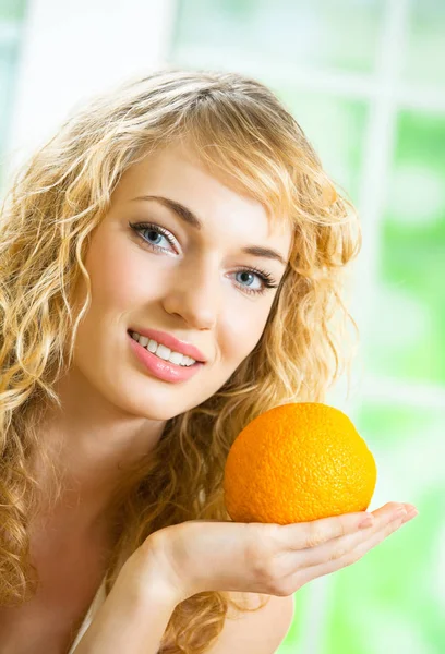 Портрет молодой женщины с апельсином дома — стоковое фото