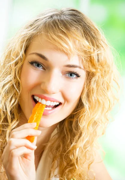 Portret van een jonge vrouw eten wortelen thuis — Stockfoto