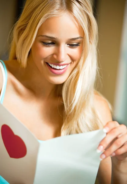 Feliz mujer sonriente, leyendo tarjeta de San Valentín — Foto de Stock