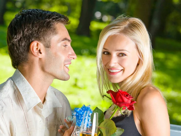 Casal com champanhe, presente e rosa, ao ar livre — Fotografia de Stock
