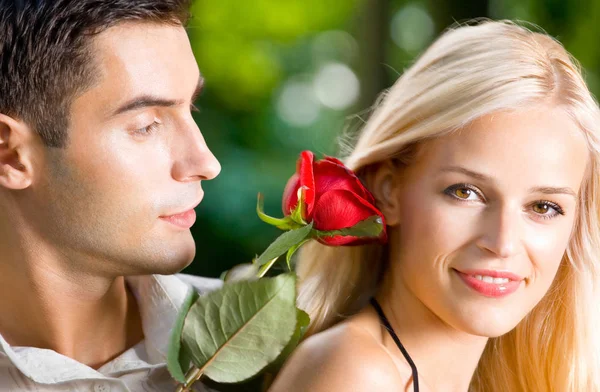 Joven pareja feliz con rosa, al aire libre Imagen de stock