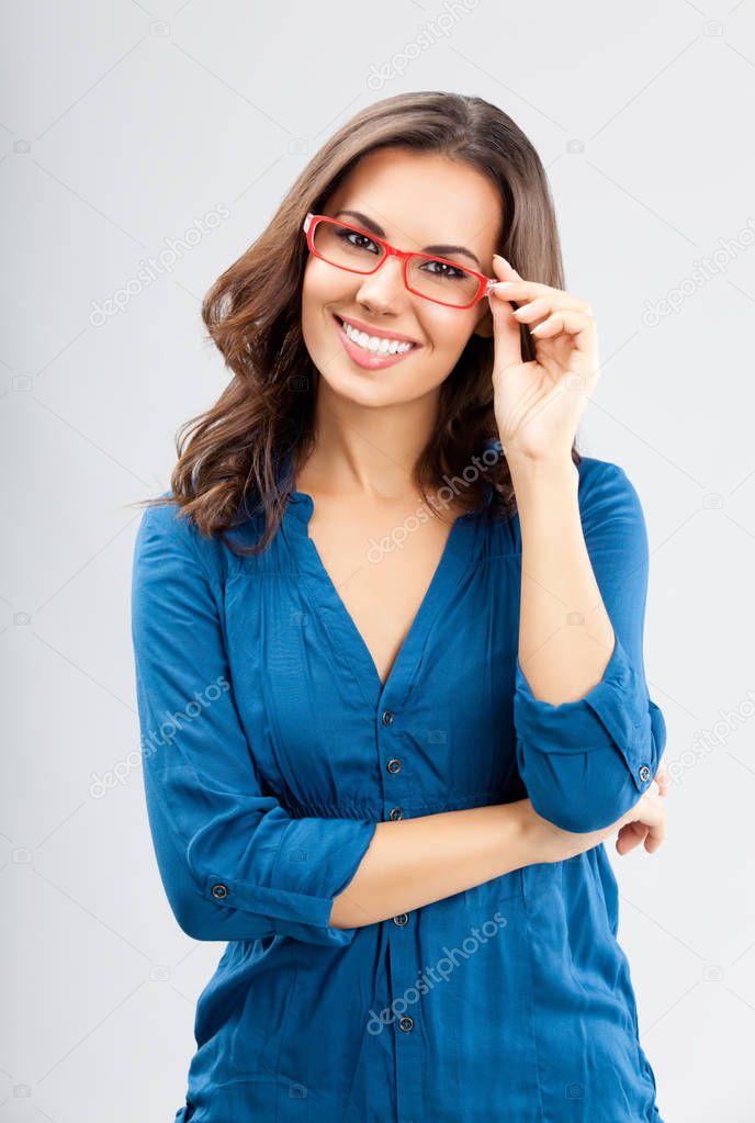 Happy businesswoman in glasses, on grey