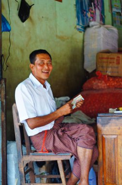 adam oturmuş ve kameraya bakıyor