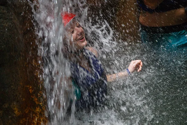 Mulher de capacete em pé sob cachoeira — Fotografia de Stock