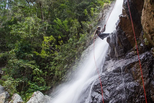 Man doing mountain climbing on waterfall — Stock Photo, Image
