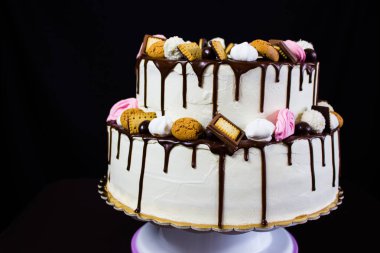 Beyaz kremalı pasta çikolata sosu ile. Beyaz kremalı pasta kurabiye, beze ve aşağı akan buzlanma çikolata ile dekore edilmiş Modern iki katmanı. İki düzey yuvarlak pasta.