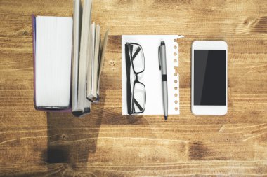 Wooden table with smartphone and book
