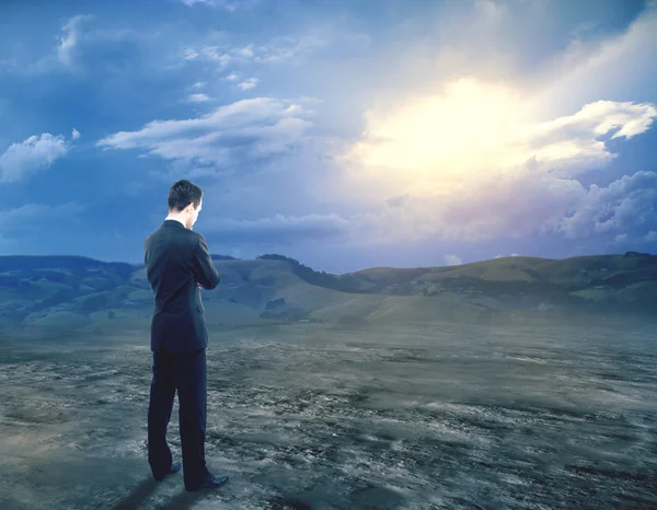 Pensivo jovem empresário de terno em pé no fundo da paisagem com luz solar. Conceito de investigação — Fotografia de Stock