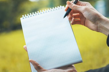 Woman writing in notepad outside