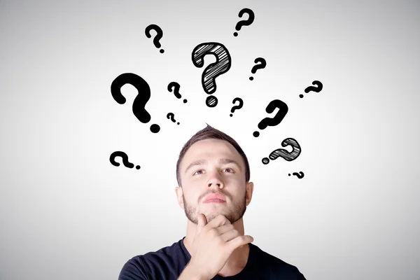 Thoughtful man with question marks — Stock Photo, Image