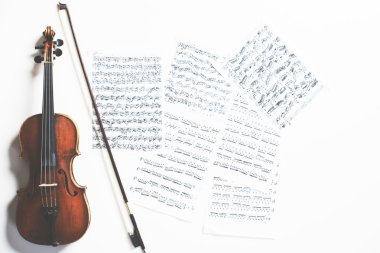 Full length violin and bow on sheet music background. Music concept clipart