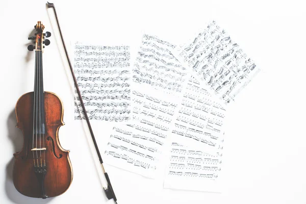 Full length violin and bow on sheet music background. Music concept