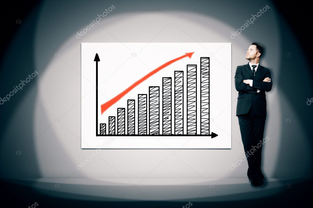 Businessman looking at business chart illuminated with spot light. Success concept