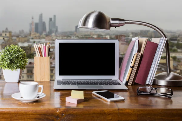 Fechar o local de trabalho do peitoril da janela criativo com laptop em branco, celular, lâmpada de mesa, xícara de café, suprimentos e outros itens no fundo vista da cidade. Faz asneira. — Fotografia de Stock