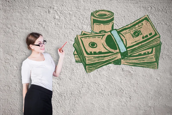 Attraktive junge Geschäftsfrau beim Betrachten einer kreativen Dollarschein-Skizze auf konkretem Hintergrund. Finanzierungskonzept — Stockfoto