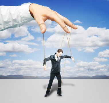 Hand controlling businessman as puppet on sky background. Control concept clipart