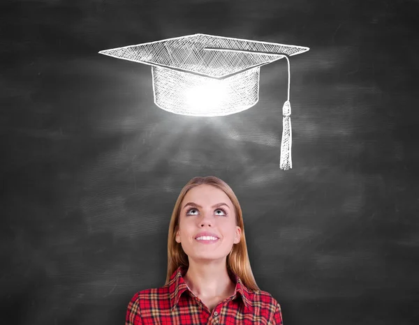 Mujer bastante caucásica en camisa casual mirando hacia arriba en el fondo de pizarra con boceto de mortero creativo. Concepto de graduación —  Fotos de Stock