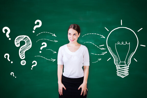 Привлекательная молодая женщина на фоне доски с креативной лампочкой и эскизом вопросительных знаков. Идея концепции
