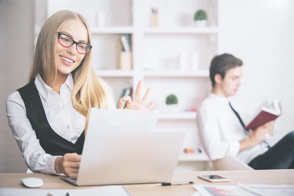 Retrato de una hermosa mujer de negocios sonriente en el lugar de trabajo mirando el documento y mostrando un signo aceptable con la mano. Concepto de éxito — Foto de Stock