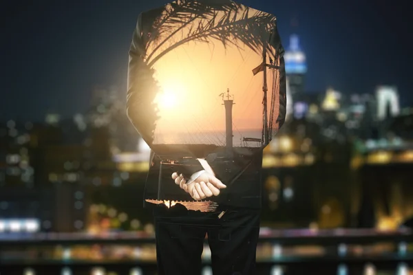 Vista trasera de un joven hombre de negocios soñando con vacaciones en un fondo borroso de la ciudad nocturna. Concepto de vacaciones. Doble exposición —  Fotos de Stock