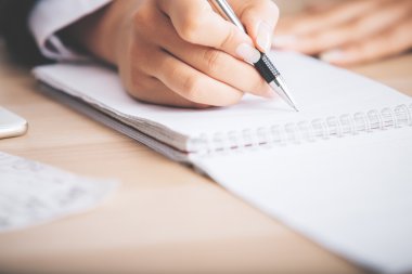 Woman's hand writing in notepad