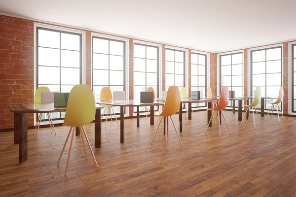 Interior em tijolo vermelho com piso de madeira, janelas com vista para a cidade e mesas com cadeiras. Conceito de sala de aula. Vista lateral, renderização 3D — Fotografia de Stock