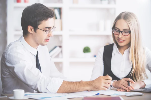 Attractive young businessman and woman in formal outfits doing paperwork in modern office — ストック写真