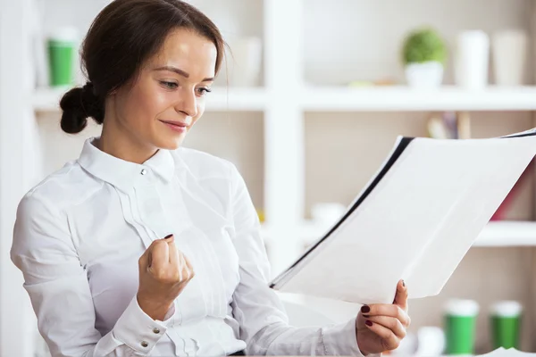 Woman with paperwork enjoying success with clenched fist — Stock Photo, Image