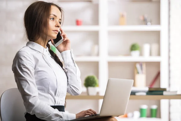 Frau am Arbeitsplatz telefoniert mit Smartphone — Stockfoto