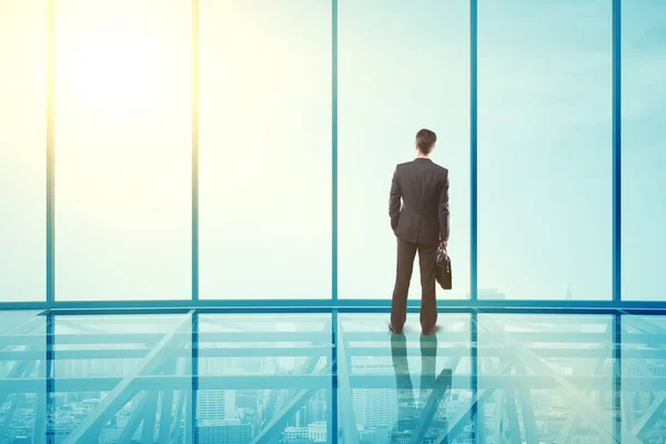 Vue arrière de l'homme d'affaires dans un intérieur moderne en verre transparent avec vue sur la ville et la lumière du soleil. Rendu 3D — Photo