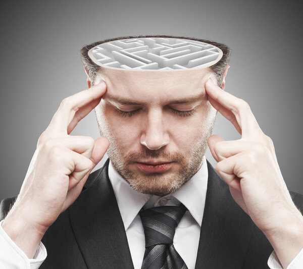 Вдумчивый молодой бизнесмен с абстрактным бетонным лабиринтом в голове. Концепция мозгового штурма
