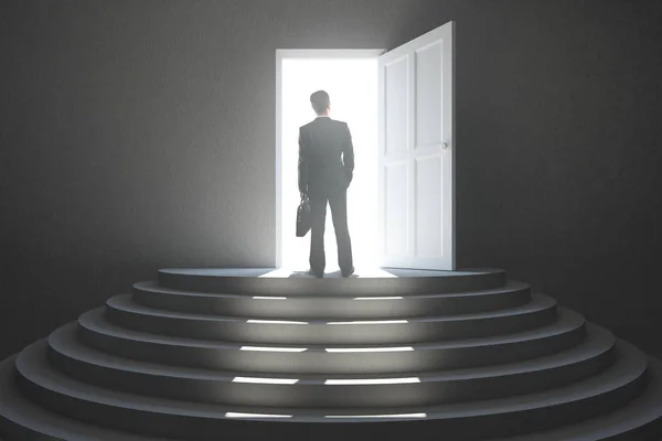 Вид ззаду молодого бізнесмена, що стоїть в абстрактному бетонному інтер'єрі зі сходами і відкритими дверима з яскравим світлом. Концепція успіху — стокове фото