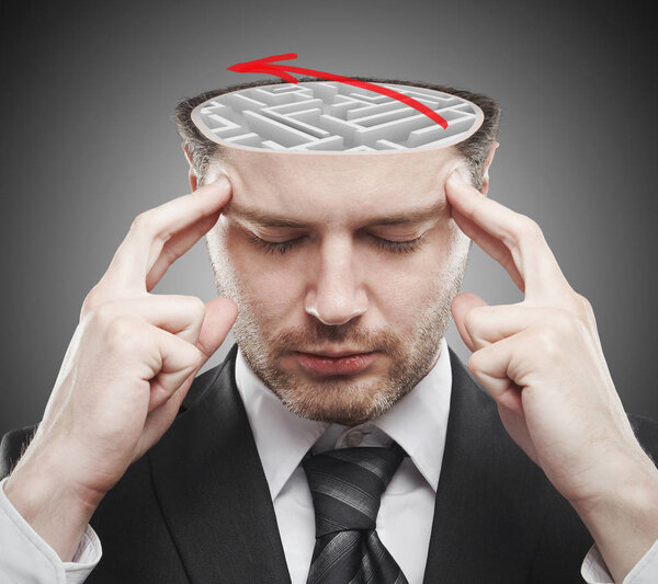 Задумчивый молодой бизнесмен с абстрактным бетонным лабиринтом и красной стрелой внутри головы. Концепция мозгового штурма
