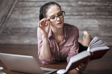 Ahşap yerde yatarken ve kitap okuma çekici genç kadın. Eğitim kavramı