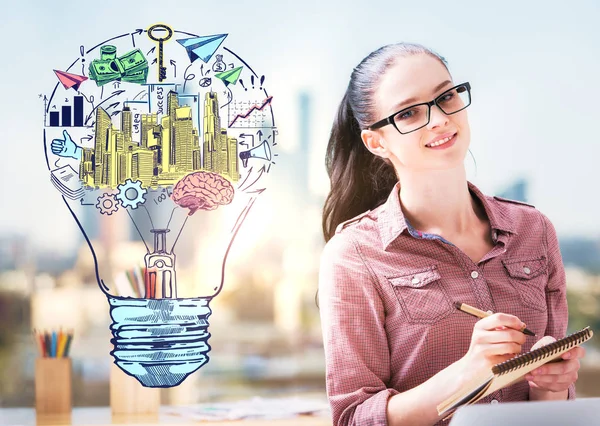 Joven mujer alegre escribiendo en bloc de notas en el fondo borroso de la ciudad con boceto de negocio creativo dentro de la bombilla. Concepto de éxito — Foto de Stock