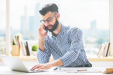 Yakışıklı olan dizüstü bilgisayar kullanarak telefon