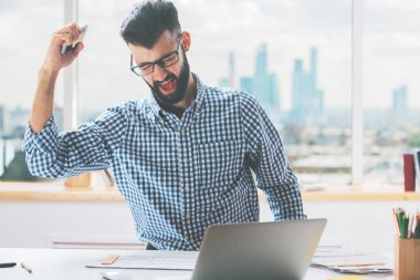 İşyeri telefon ve gösteren yumruk, 'Evet' jest konuşmak yakışıklı genç erkek. Başarı kavramı 