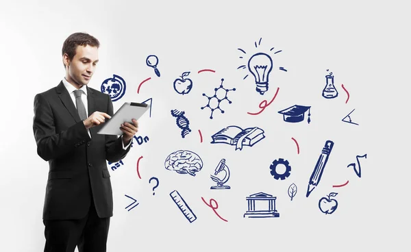 Stattliche junge Geschäftsmann mit Tablet auf weißem Hintergrund mit wissenschaftsbezogenen Symbolen. Bildungskonzept — Stockfoto